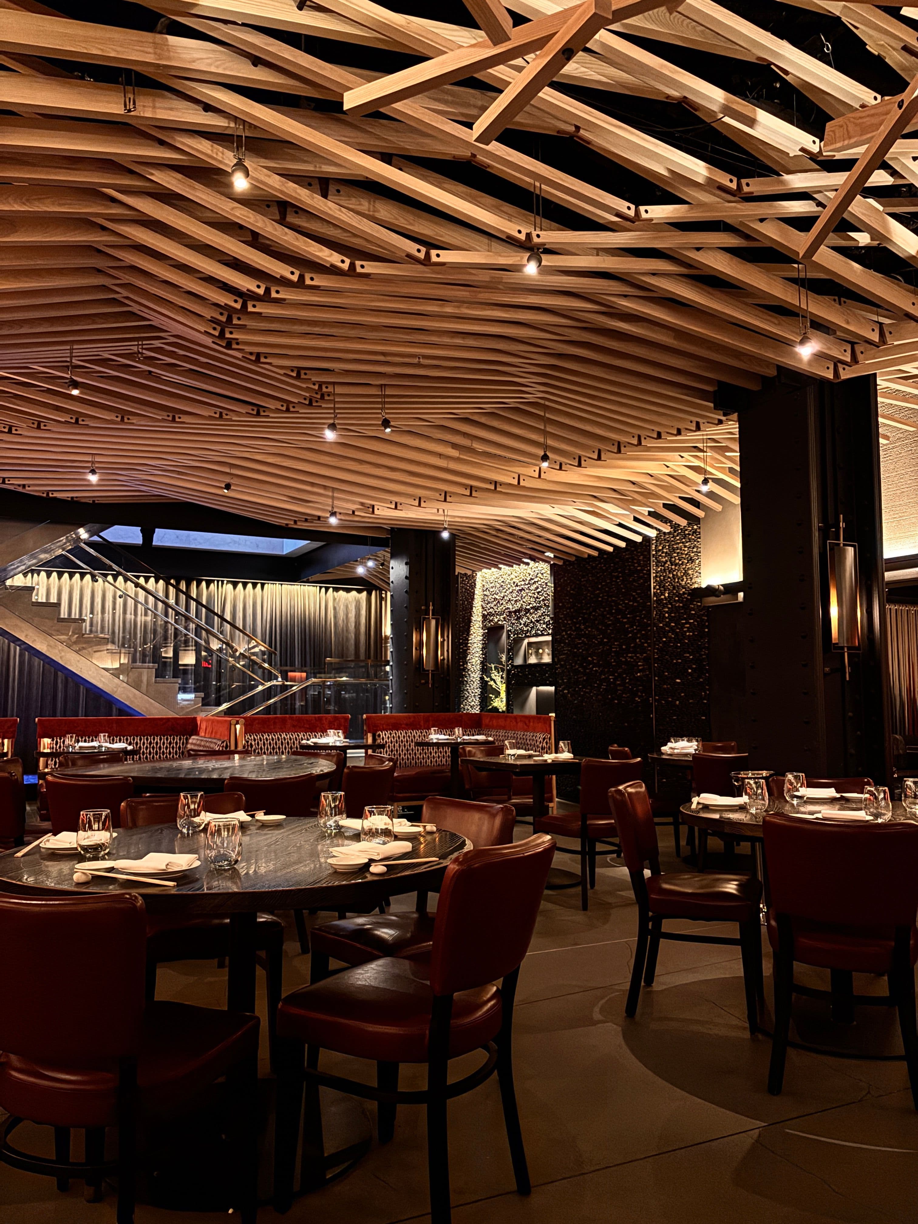 Warm restaurant interior with sculptural wooden ceiling